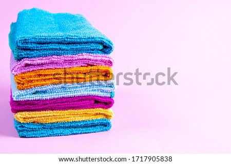 Multi-colored towels on a pink background. Pink, beige, yellow, orange and blue towels. Place for writing. House order