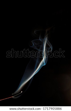 Puffs of smoke from a candle against a dark background
