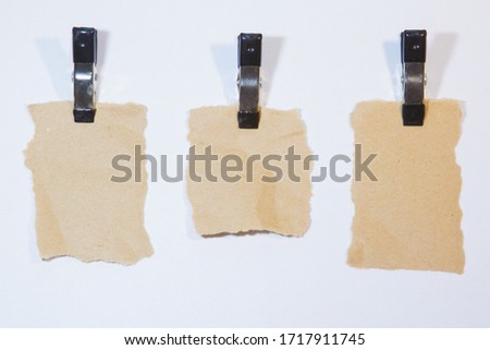 Collection of brown paper pieces with alligator clippers on the white background