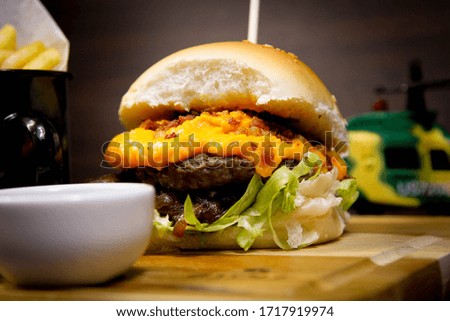 
Delicious handmade beef burger, hot dog, milks, french fries, dumplings, pates, vegetables on wooden table isolated on black background.