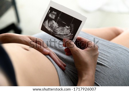 Pregnant woman holding and looking sonogram or ultrasonography picture of her unborn baby Royalty-Free Stock Photo #1717926007