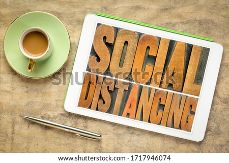 social distancing word abstract in vintage letterpress wood type on a digital tablet with coffee,  protective measures during covid-19 corona virus pandemic, work from home concept