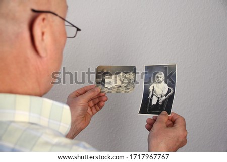 old man’s male hands hold and looks at children's photographs of his and his sisters, made in 1963 - 1964, genealogy concept, ancestral memory, family ties, childhood memories