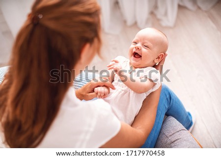 Happy loving family. young mother is sitting on an easy armchair with small child. woman smiles, plays and hugs baby. concept motherhood. Mom spends fun gymnastics with her newborn daughter. top view