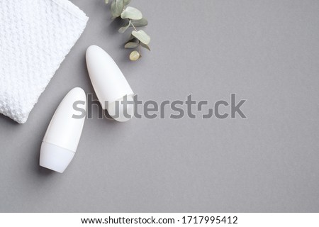 Deodorant bottles mockup with towel and eucalyptus leaf on grey background. White antiperspirant packaging, female sweat protection product concept