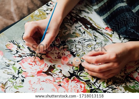 Painting by numbers concept. Young girl enjoying coloring picture by numbers. Creative hobby. Leisure activity at home during self-isolation COVID-19