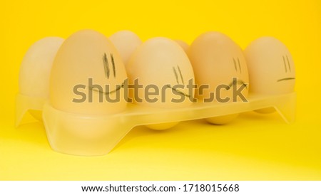 Eggs in a tray, with smiles,in the form of smiles,multi-colored,on a bright yellow background,funny emotions. Close-up.Chicken with shell.