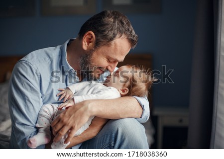Middle age Caucasian father kissing sleeping newborn baby girl. Parent holding rocking child daughter son in hands. Authentic lifestyle parenting fatherhood moment. Single dad family home life. Royalty-Free Stock Photo #1718038360