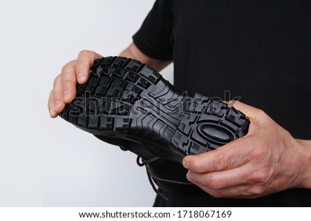 man holds in his hands a black work boot made of genuine leather with a reinforced cape, the concept of special shoes for different professions Royalty-Free Stock Photo #1718067169