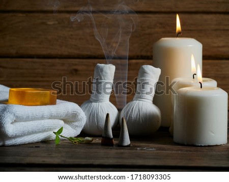 Spa set with herbal compress ball and the smoke of burning frankincense on wooden table in the dark. Royalty-Free Stock Photo #1718093305