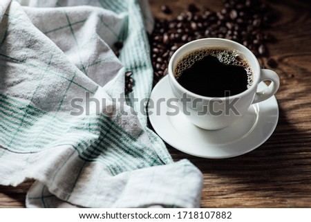 Hot black coffee cup and coffee beans on wooden background with natural light in the morning