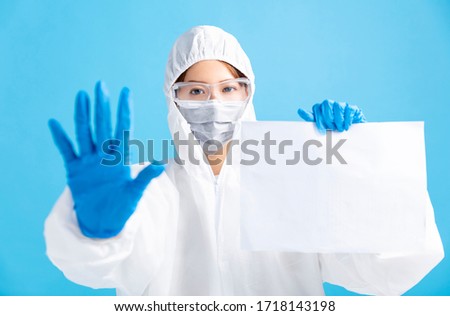 female nurse wearing medical mask with safety glasses and in white protective suit. showing blank billboard