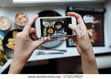 Woman taking a photo of breakfast with smartphone, hands hold phone, frome above