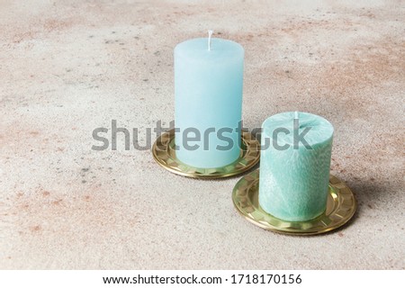 Blue candles on brass candlesticks, coasters, small dishes on concrete background. Copy space for text and photography props.