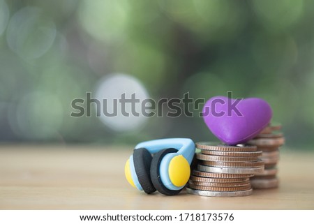 Violet heart model on coins stack with headphones. Saving for buy something concept