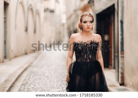 A stylish bride in a black wedding dress poses in the ancient French city of Avignon. Model in a beautiful black dress. Photo shoot in Provence.