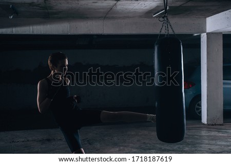 Silhouette picture of young female kicking the boxing bag