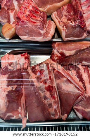 Fresh slices of raw pork meat on counter in supermarket, nobody