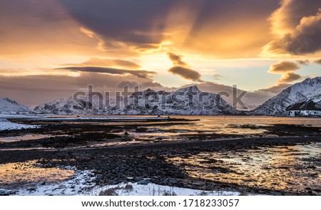 panoramic view in norway on the lofoten islands with warm colors and snow mountains