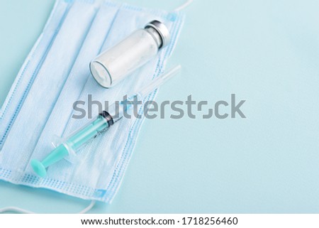 closeup medical syringe, glass ampoule, medical mask on blue background, vaccination, inoculation concept, copy space Royalty-Free Stock Photo #1718256460