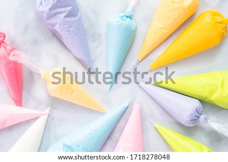 Flat lay. Piping bags with pastel color royal icing to decorate Easter sugar cookies.
