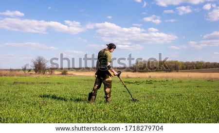 Man with a shovel and a metal detector in a meadow looking for treasures and coins Royalty-Free Stock Photo #1718279704