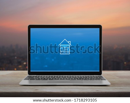 Work from home flat icon with modern laptop computer on wooden table over blur of cityscape on warm light sundown, Business social distancing online concept