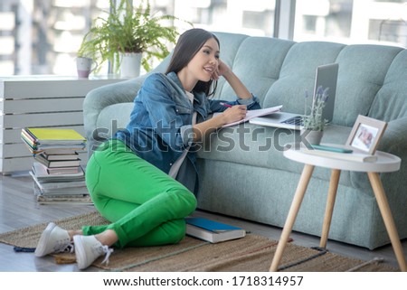 Feeling good. Young woman in green pants sitting on the floor and looking relaxed