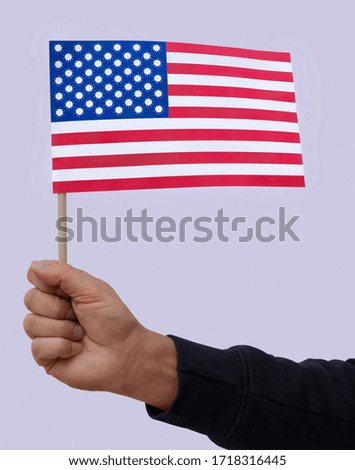 Hand holding the USA flag whose stars are represented by the symbol of the Covid-19 virus