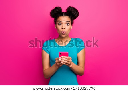 Photo of pretty shocked millennial dark skin lady hold telephone hands check blog bad comments open mouth wear blue casual t-shirt isolated bright pink color background