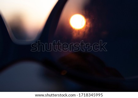 Photo in bokeh style. The photo shows sunglasses, through which you can see the sunset. The photo was taken in the city.