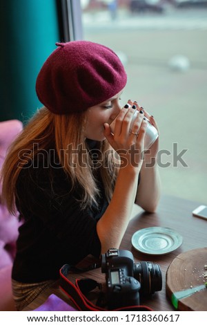 The girl in the cafe is drinking coffee. Photo taken with selective focus, tinting and noise effect.