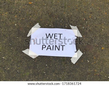 Wet Paint sign plastered to a wall with sticky tape. 