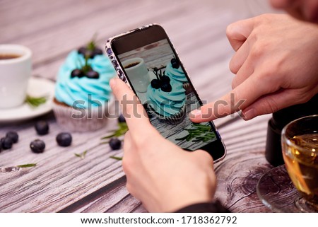 Food photography for the blog. Female hands shoots a photo of cupcakes on a smartphone.Food blogger shoots coffee and cupcakes. Food blog. Selective focus. Royalty-Free Stock Photo #1718362792