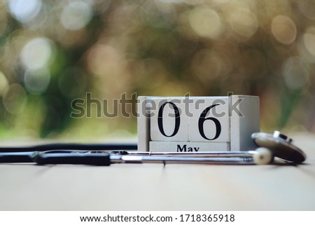 close up wooden calendar and stethoscope on wood table, 6 may text, medical and healthcare, national nurse day concept