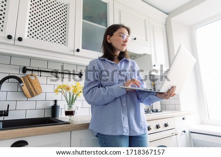Young woman in scandinavian style kitchen interior and working on a laptop. Home quarantine during Covid-19 pandemic Coronavirus. Distance work from home concept. Female freelancer working at home