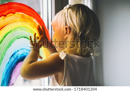 Little girl hands touch painting rainbow on window. Child Art and Creative. Kids leisure at home, childcare, safety joy symbol. Positive visual support during quarantine Coronavirus Covid-19 at home.