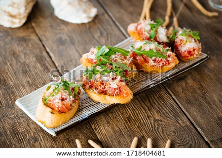 Closeup on italian appetizer bruschettas with tomato sauce and parmesan cheese on the wooden table, horizontal Royalty-Free Stock Photo #1718404681