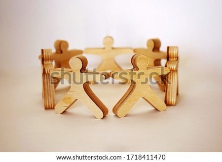 Wooden little men stand in the circle and hold hands together on the white background Royalty-Free Stock Photo #1718411470