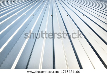 Low angle view of the silvery warehouse wall. Metal siding, texture, close-up