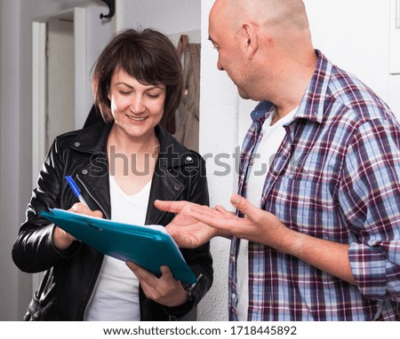 Mature man signing papers with social worker at home near the door