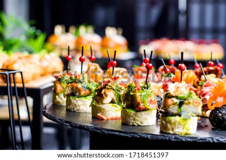 Set of beautiful canapes on black stone plates. Buffet table. Catering. Royalty-Free Stock Photo #1718451397