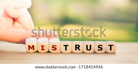 Hand turns dice and changes the word "mistrust" to "trust". Royalty-Free Stock Photo #1718454946