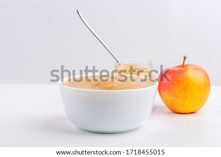 Fresh homemade applesauce in white bowl and jar with fruit puree on white table. The concept of proper nutrition and healthy eating. Organic and vegetarian food. Baby food. Copy space for text Royalty-Free Stock Photo #1718455015
