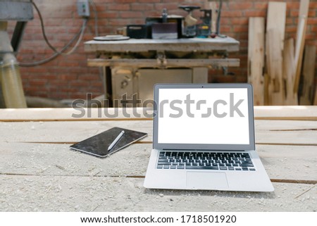 Open laptop in a woodshop with isolated screen on a wooden table Royalty-Free Stock Photo #1718501920