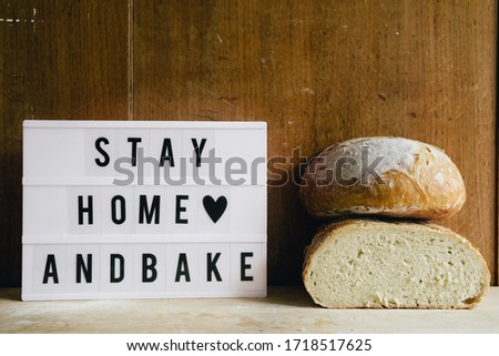 Stay home and bake covid 19 conceptual image for coronavirus pandemia,  with a lightbox texting stay home and bake,and  freshly baked bread cut in half
