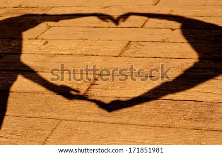 Silhouette of hands making sign heart on wood background. Concept about love and relationship