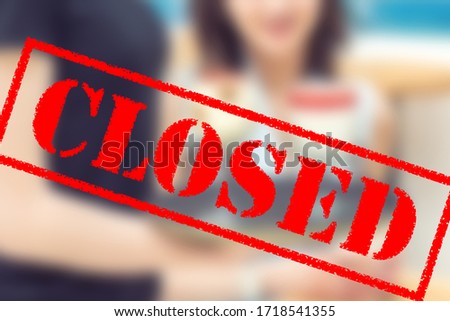 Word CLOSED on blurred background of two young women in the cafe outdoors. Coronavirus quarantine. Closed cafe outdoors.
