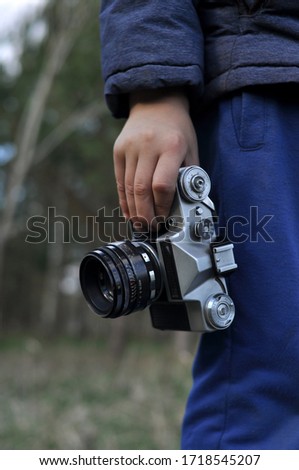 In the hand of a young man is an old camera as a symbol of old photography.