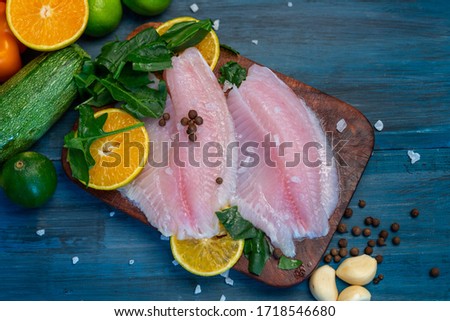 Fish fillet with orange, grain salt, pepper and spinach, on a blue wooden base, ready to cook Royalty-Free Stock Photo #1718546680